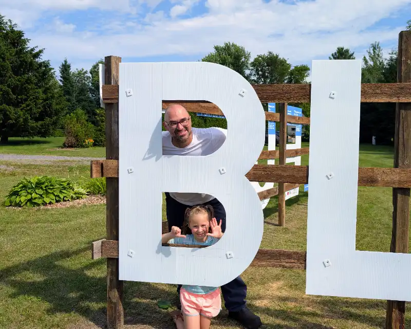 Enfants posant dans les grandes lettres blanches de la bleuetière
